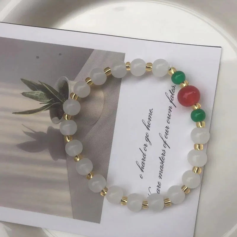 A Chinese style glass bracelet with bamboo leaf and bead designs on a wrist.