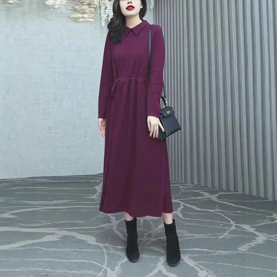 A purplish red plus size long sleeve dress with a long skirt, shown on a model.