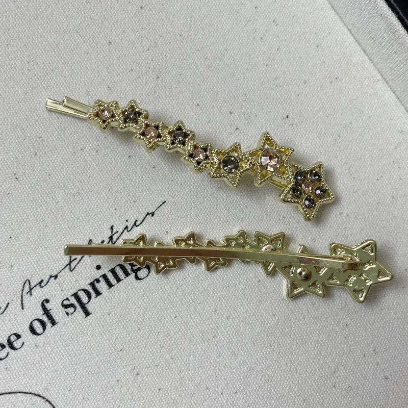 Gold-coloured alloy hair barrette with rhinestone star charm, shown clipped to hair.