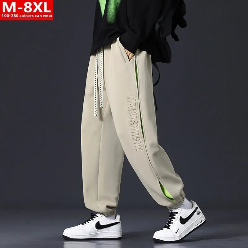 Man wearing loose grey-green cotton trousers with a banded ankle cuff and stitching detail.