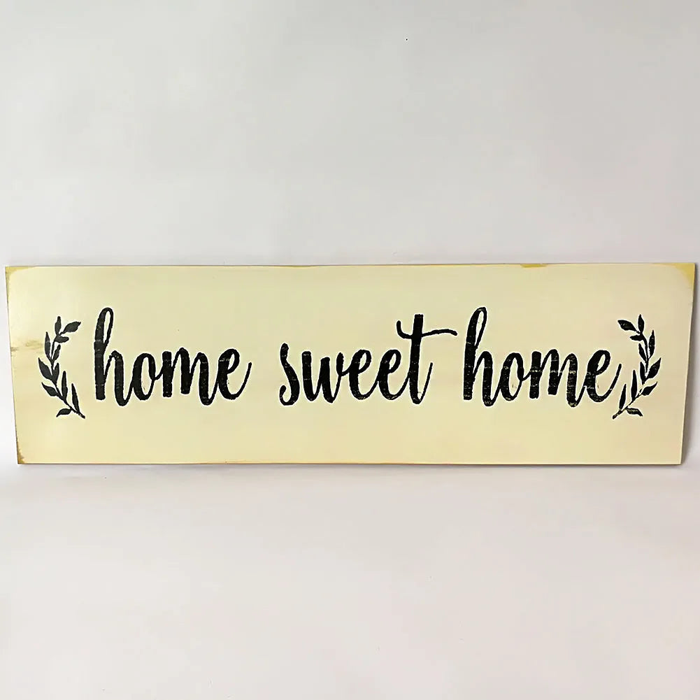 Black wooden wall plaque with carved white HOME SWEET HOME text, showing its rectangular shape.