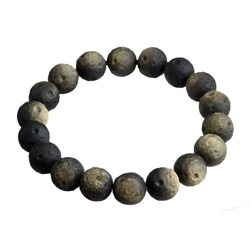 Close-up of an obsidian crater ball bead bracelet showing textured surface from grinding treatment, in silver stone meteorite finish.