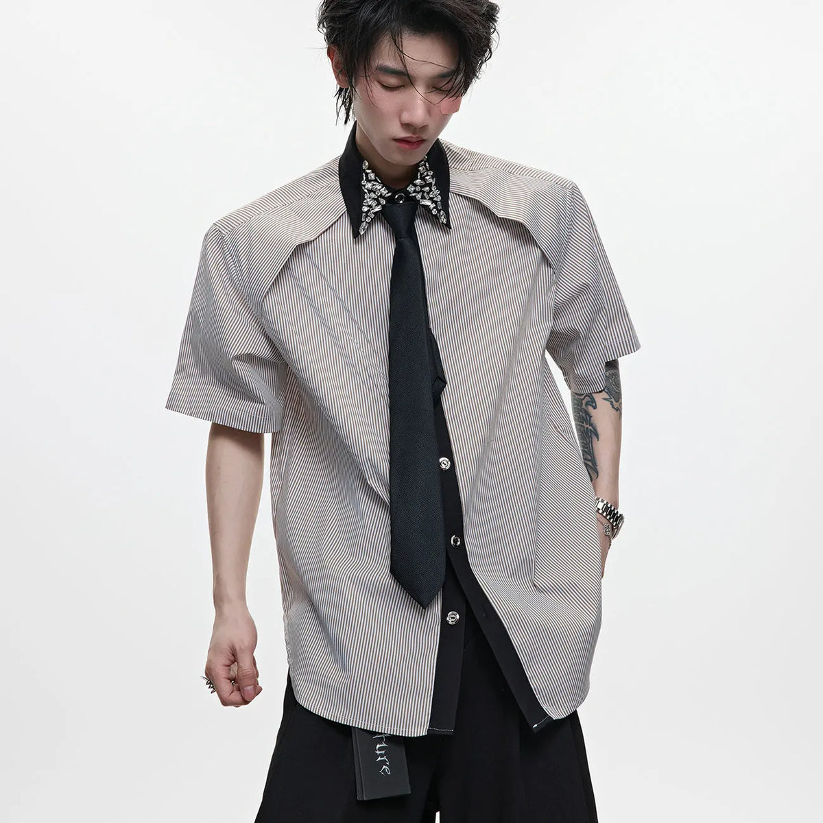Men's blue and khaki patchwork striped shirt with diamond tie and quilted details, showing loose fit and flip collar.