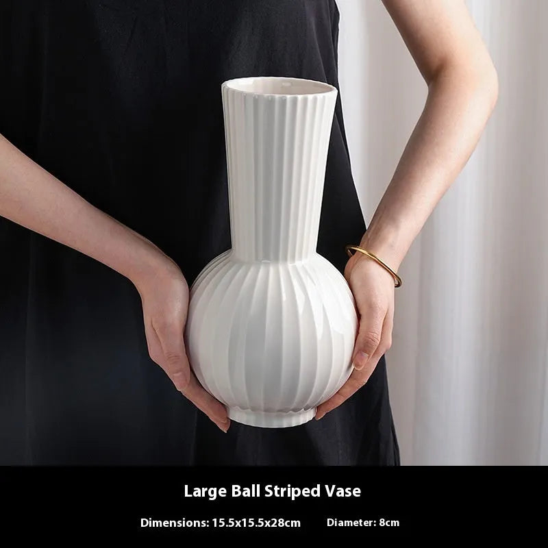 White ceramic ball-shaped vase with striped American country design on a table.