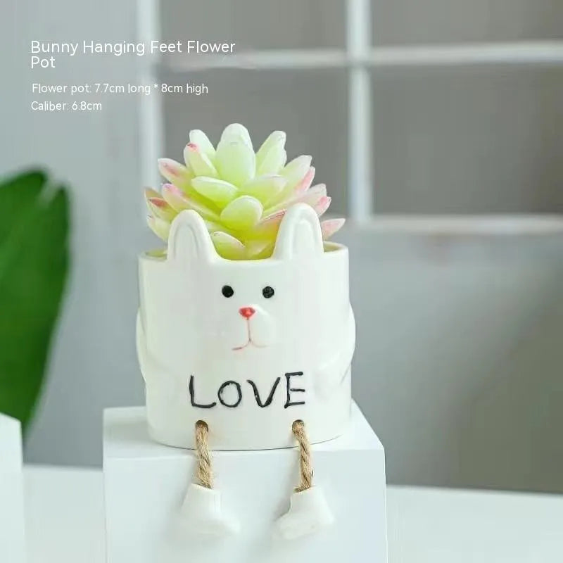 Ceramic cartoon-style succulent flowerpot with hanging foot design on desktop