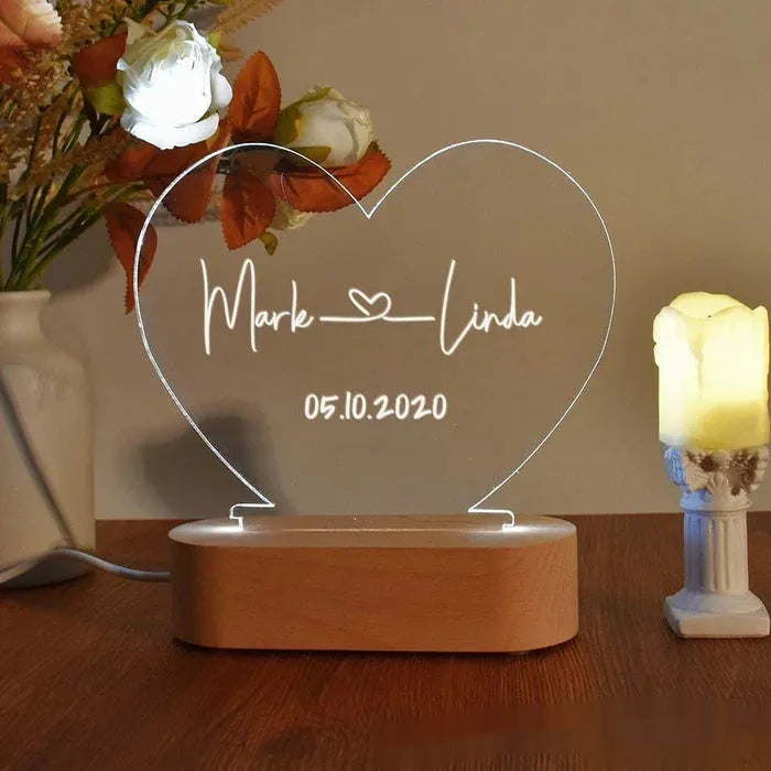 Custom clear acrylic night light with engraved names, lit by an LED base.