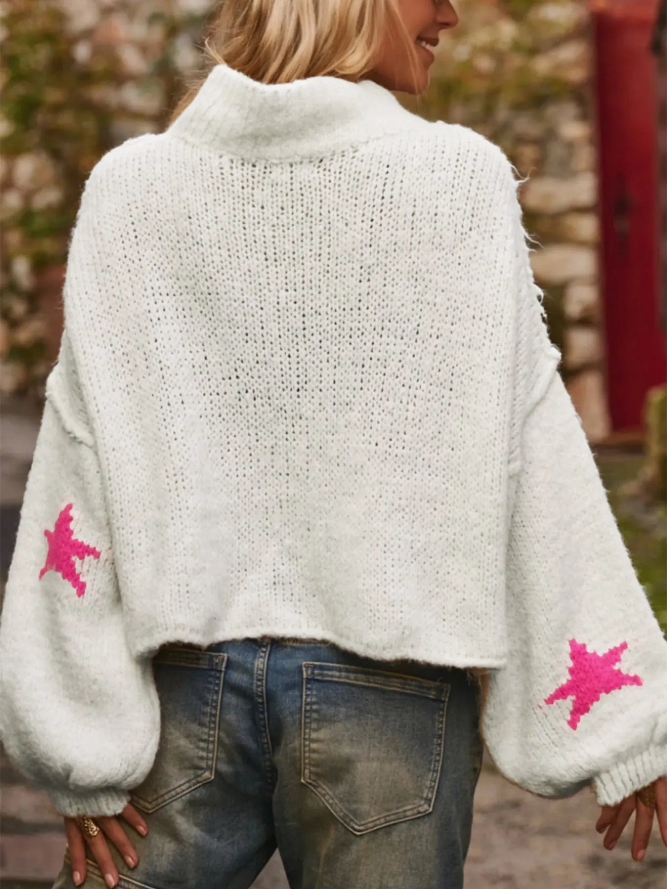 White women's loose turtleneck pullover sweater with a black five-pointed star pattern on the front.