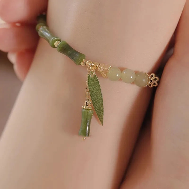 A Chinese style glass bracelet with bamboo leaf and bead designs on a wrist.