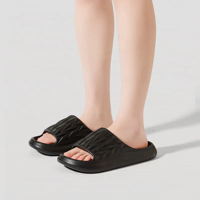 Pair of grey EVA foam slippers with leaf texture pattern and non-slip sole.
