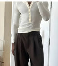 Men's cream apricot coloured ribbed long-sleeve henley top with button placket on a hanger.