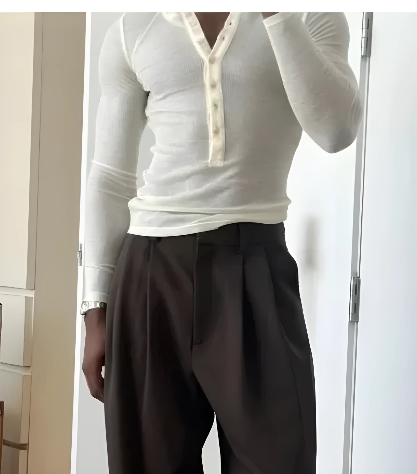 Men's cream apricot coloured ribbed long-sleeve henley top with button placket on a hanger.