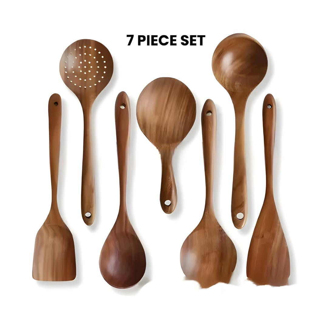 Set of seven natural wooden kitchen spoons and spatulas arranged together on a table.