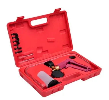 Aluminium manual vacuum air blow gun and suction tool for automotive repair on a workshop bench.