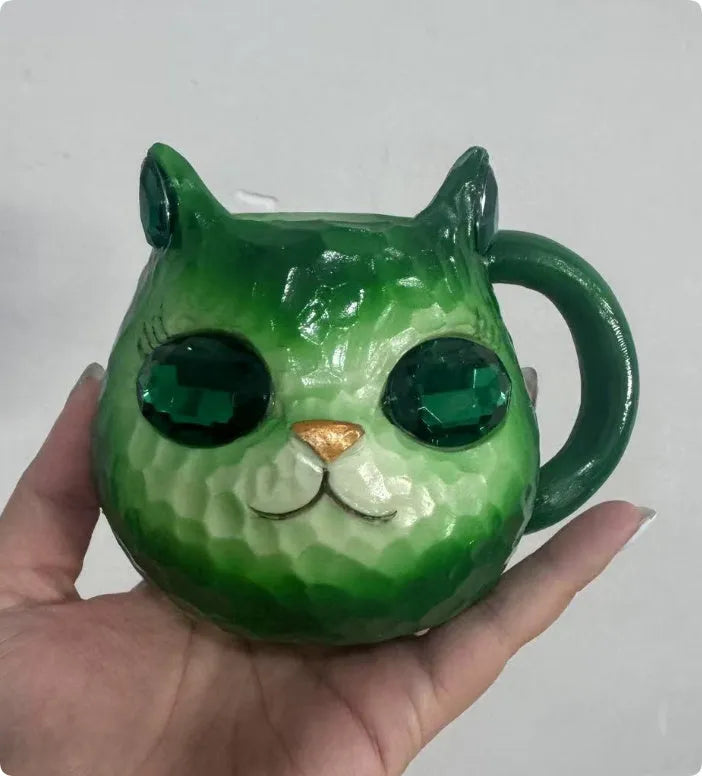 Small resin cat cup figurine in purple, green, blue, or pink colour on a shelf.