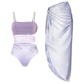Purple one-piece swimsuit with hollow design and matching wrap skirt on a model.