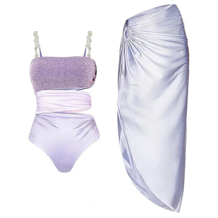 Purple one-piece swimsuit with hollow design and matching wrap skirt on a model.