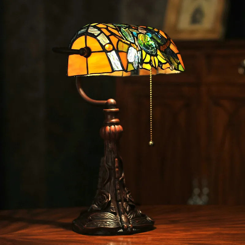 10-inch Tiffany style table lamp with coloured stained glass shade and resin base on a desk.