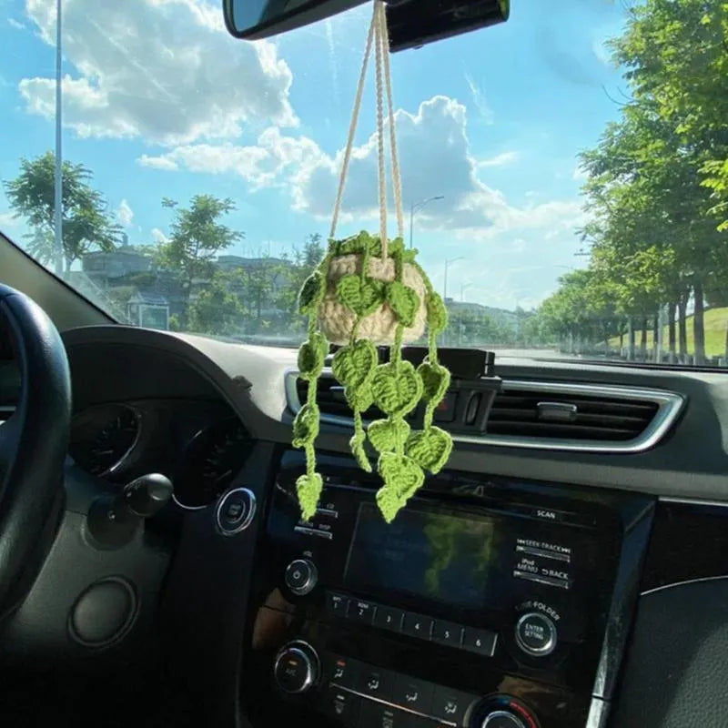 Green and white knitted car plant decoration with hanging rope on car dashboard