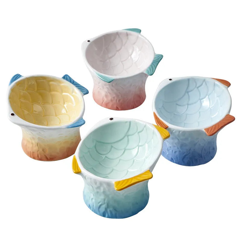 Blue fish-shaped ceramic cat bowl with tilted angle and elevated sides on a white background.