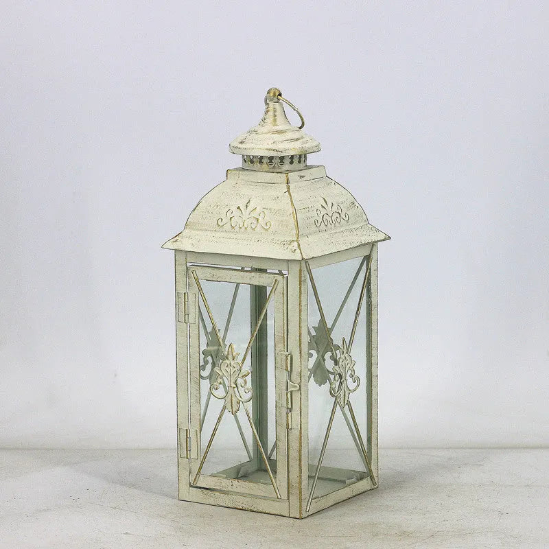 Black wrought iron floor lantern with tempered glass panels, standing on a patio.