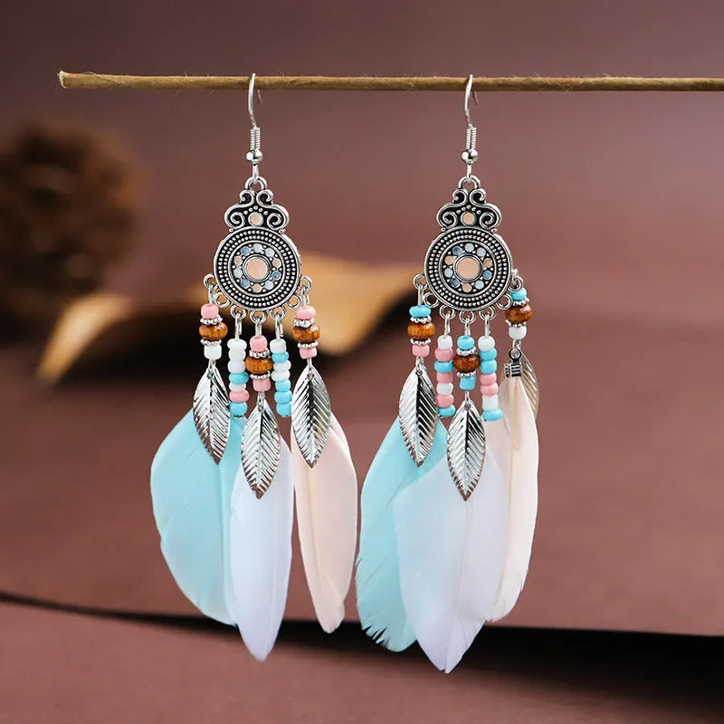 Close-up of a pair of bohemian-style feather-shaped earrings with a leaf pattern, in an alloy electroplated finish.