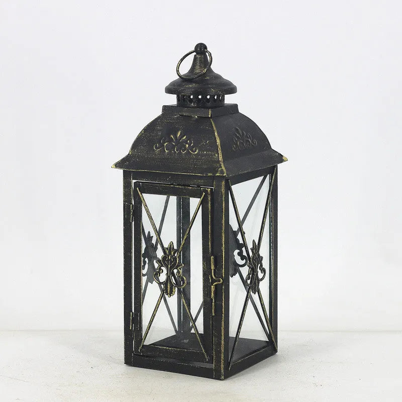 Black wrought iron floor lantern with tempered glass panels, standing on a patio.