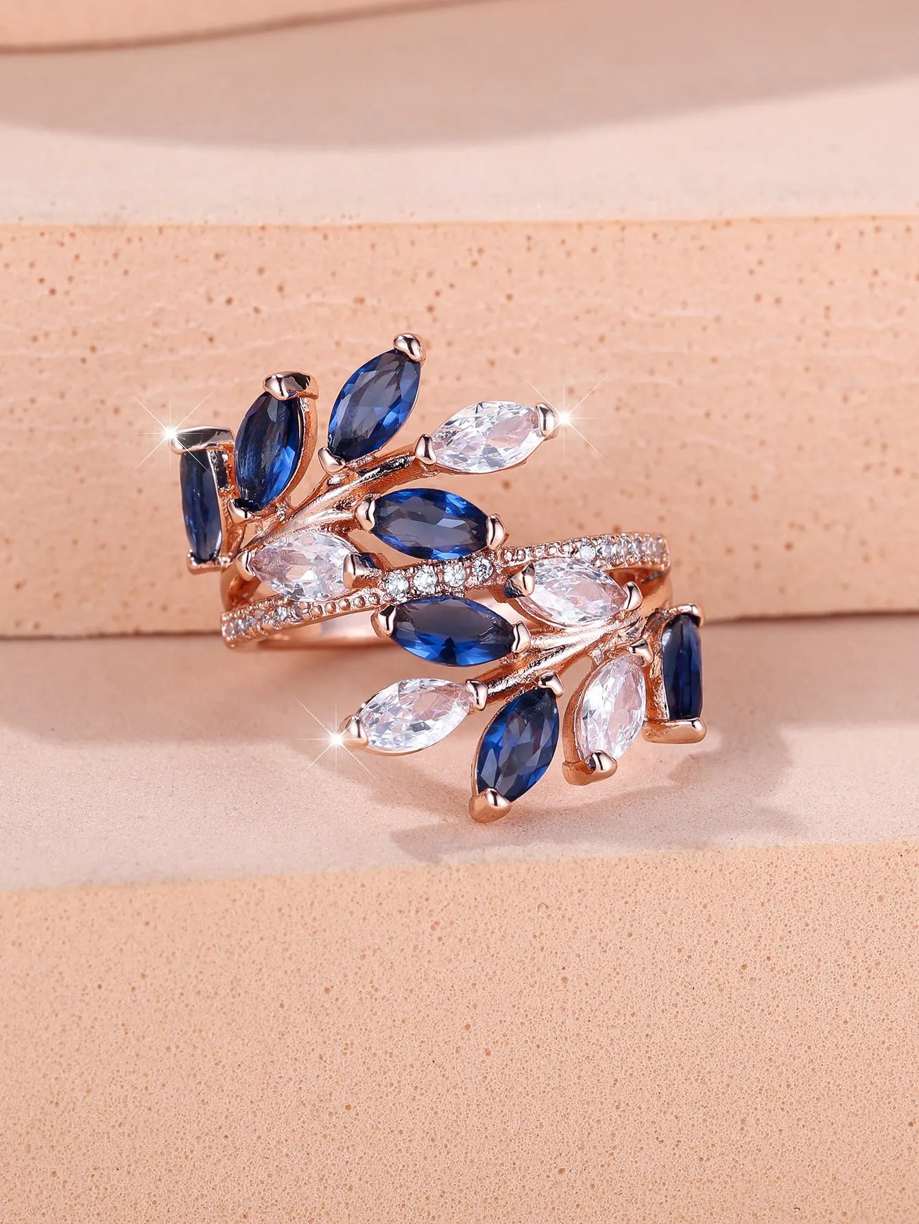 Adjustable opening copper leaf fashion ring with sparkling zirconia stones in a rose gold finish.