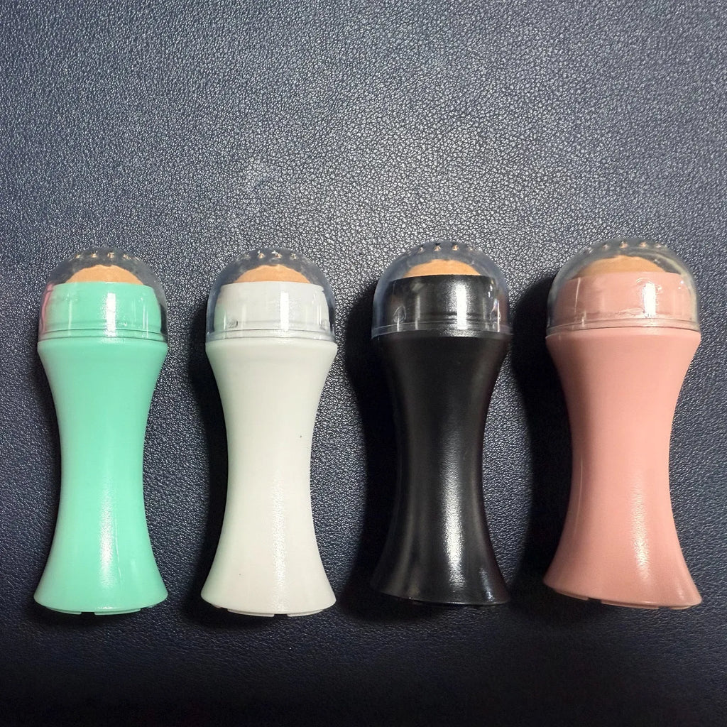 Portable volcanic stone oil-absorbing facial roller in black, green, pink, or white on a plain background.