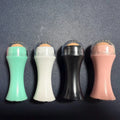 Portable volcanic stone oil-absorbing facial roller in black, green, pink, or white on a plain background.