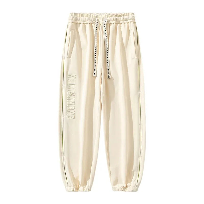 Man wearing loose grey-green cotton trousers with a banded ankle cuff and stitching detail.