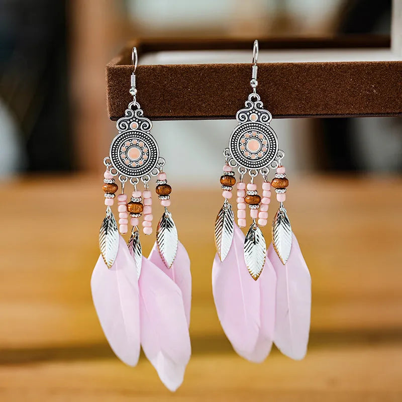 Close-up of a pair of bohemian-style feather-shaped earrings with a leaf pattern, in an alloy electroplated finish.