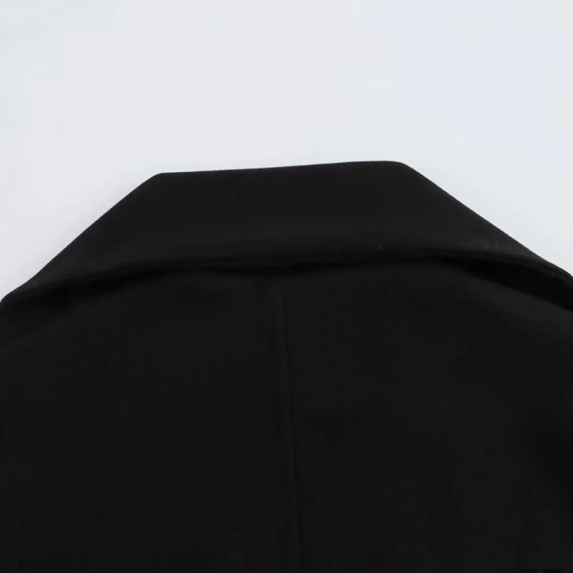 Women's long black coat with a detachable grey artificial fur collar, showing longline silhouette and side pockets.