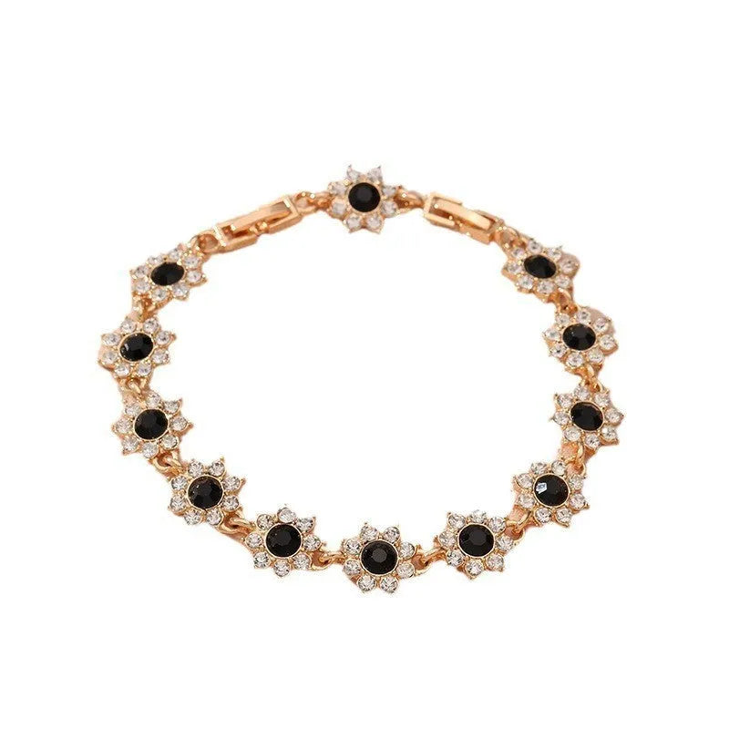 Gold tone flower-shaped bracelet with blue crystal gems on a wrist.