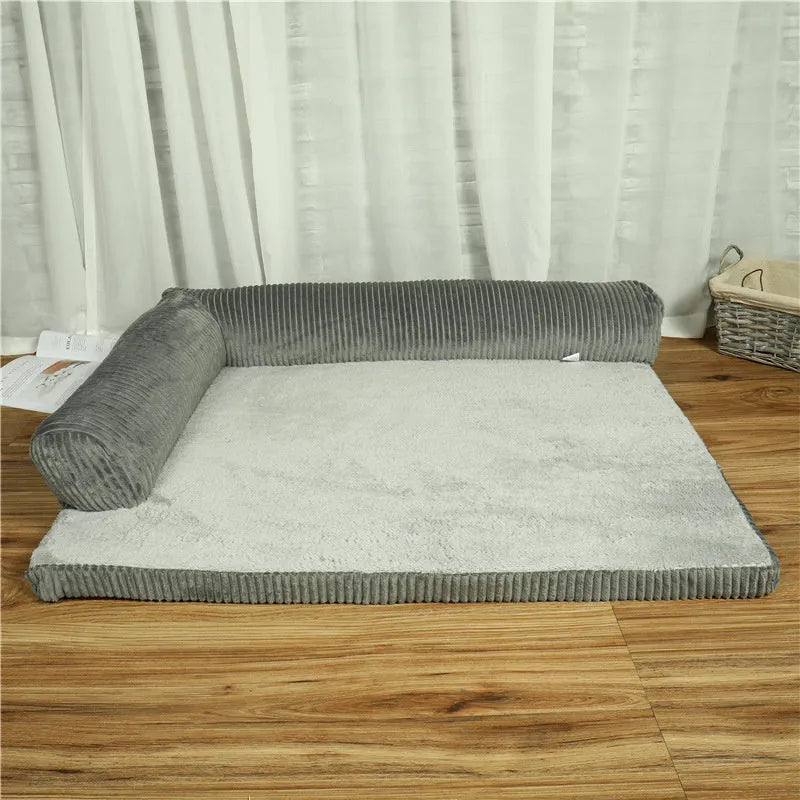 Corduroy dog sofa bed with bolster, shown in grey, placed on a wooden floor.