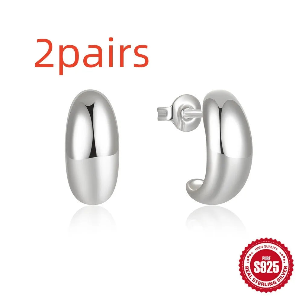 A pair of glossy C-shaped stud earrings in sterling silver, shown in gold and silver colour options.