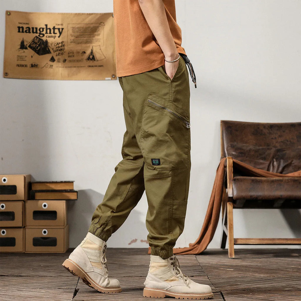 Men's khaki coloured loose-fit tapered harem pants with a small ankle band and elasticated waist.