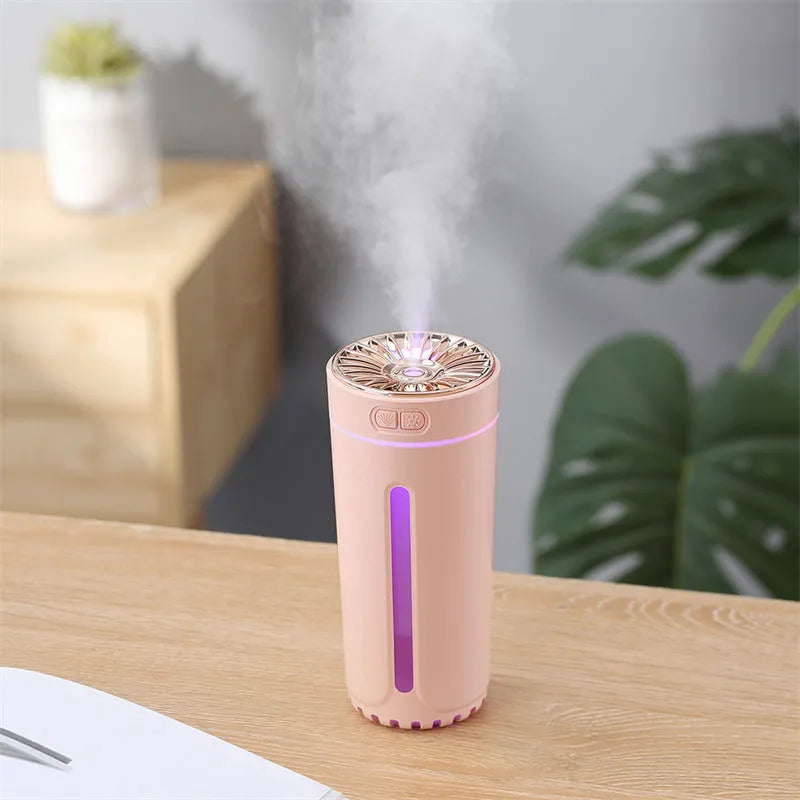 Black portable USB rechargeable car humidifier with colourful lights on a desk next to a cup