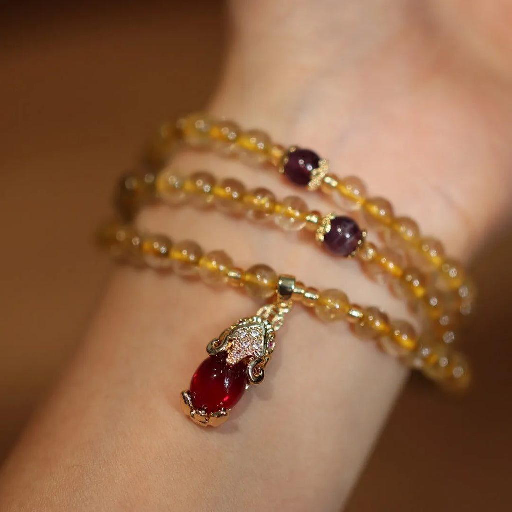 Brazil gold rutilated quartz bracelet with three gold circles in a Chinese style, hanging from chopsticks.