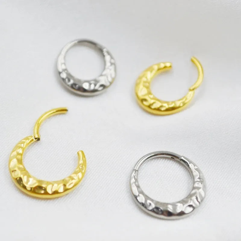 Close-up of a titanium alloy nose ring with concave-convex texture in a gold anodised finish.