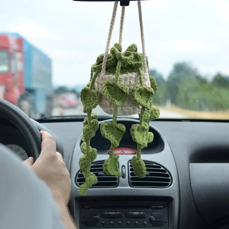Green and white knitted car plant decoration with hanging rope on car dashboard