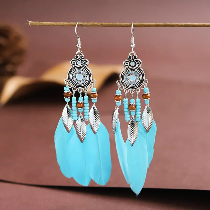 Close-up of a pair of bohemian-style feather-shaped earrings with a leaf pattern, in an alloy electroplated finish.