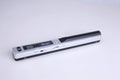 Plastic handheld USB document scanner on a desk next to papers.