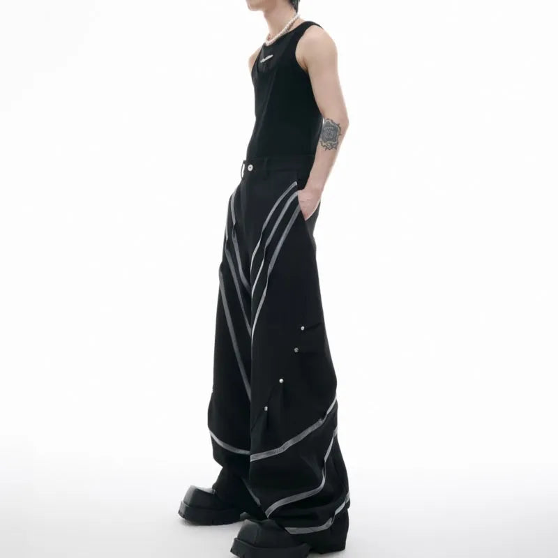 Men's black polyester trousers with metal striped rivet decoration and pleats, showing three-dimensional cut.
