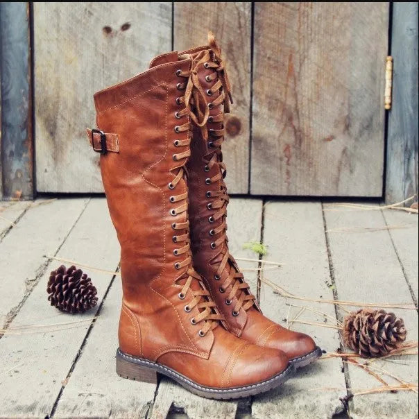 Women's black knight-style ankle boots with a cross-strap fastening across the front.