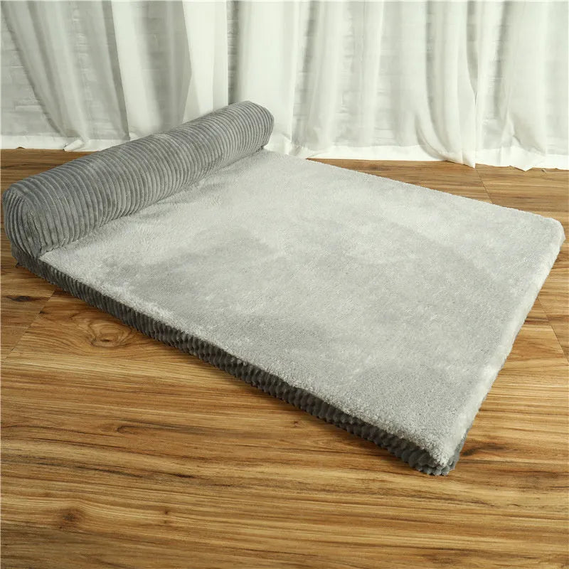 Corduroy dog sofa bed with bolster, shown in grey, placed on a wooden floor.