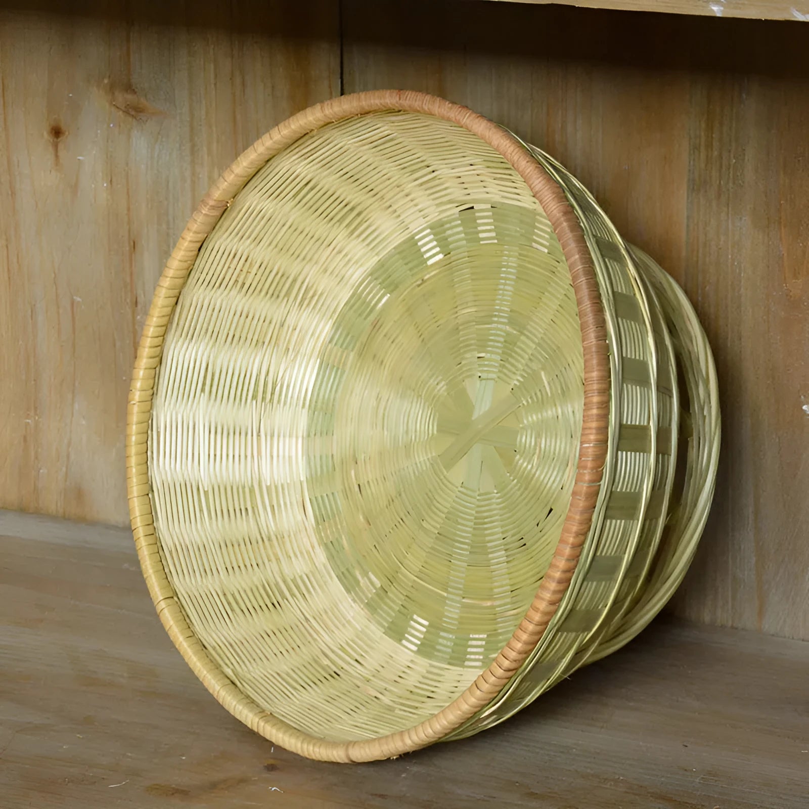 Handmade natural bamboo woven storage basket in three different sizes on a table.