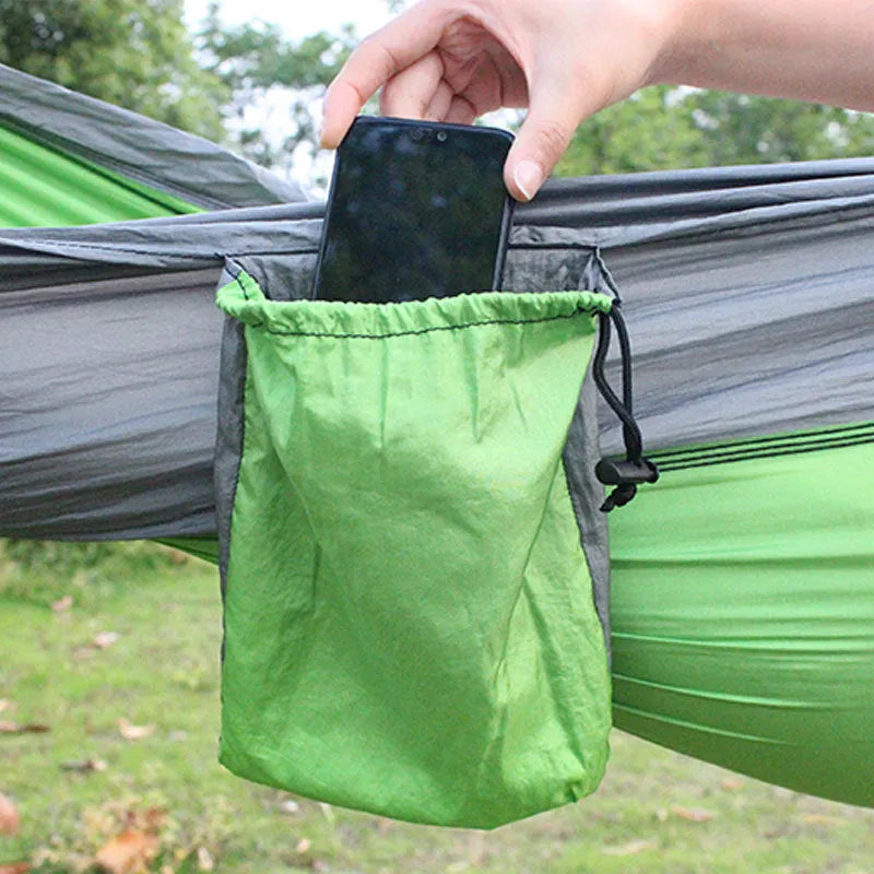 Blue nylon parachute cloth camping hammock hung between two trees outdoors.