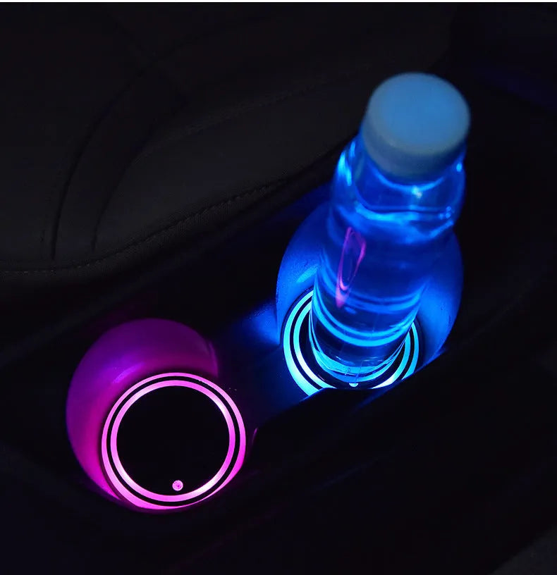 Colourful LED light-up coaster for car cup holder with USB cable on a car console.