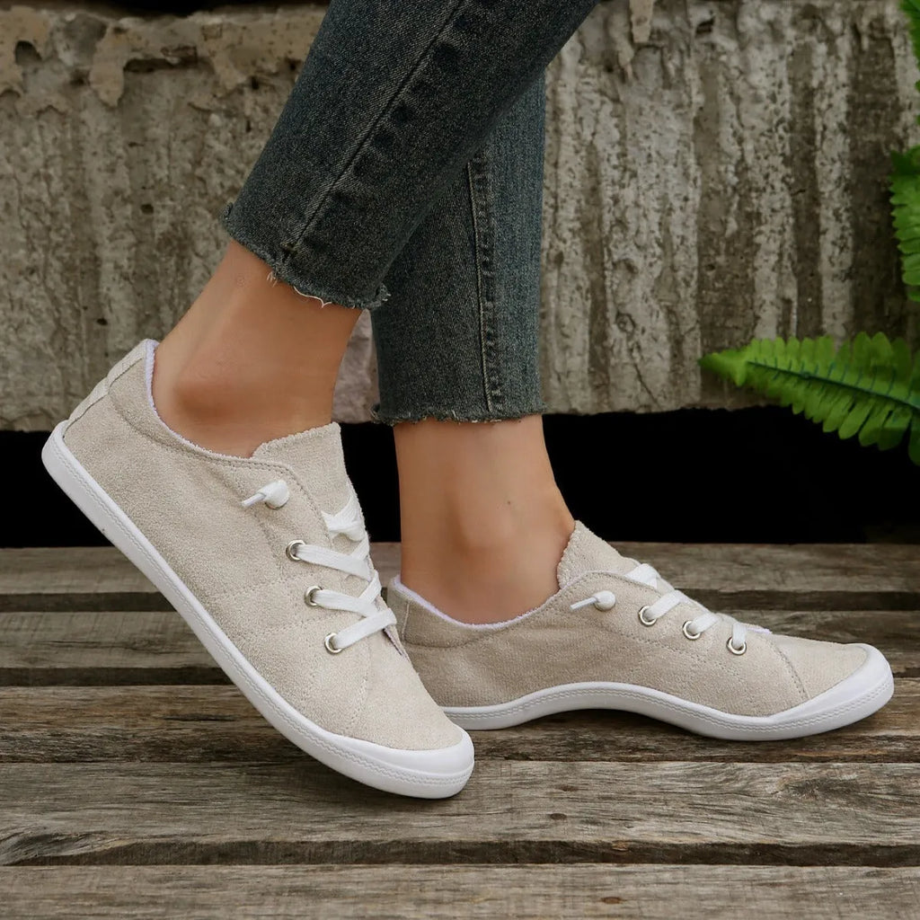 Women's low-top creamy white fabric sneakers with a wear-resistant rubber sole on a neutral background.