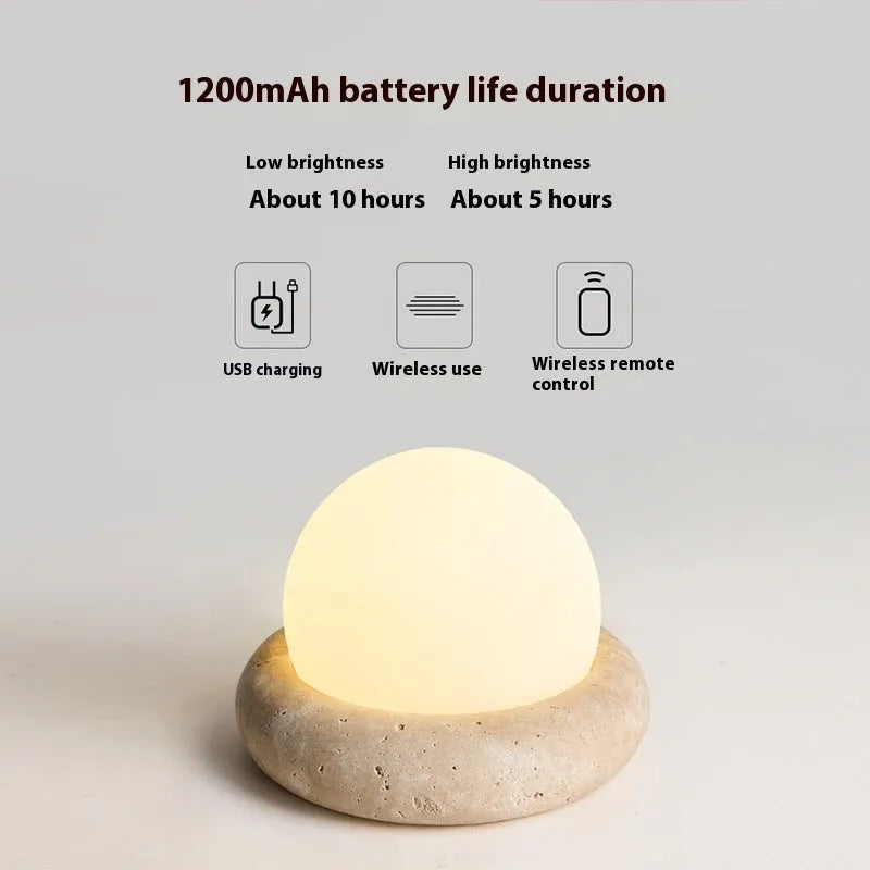 Modern cream-coloured bedside table lamp with wireless remote control on a nightstand.